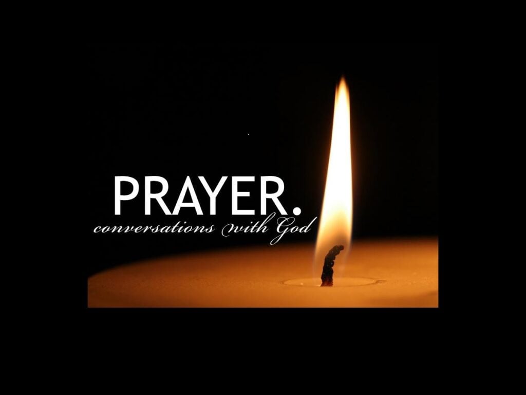 A black background, with the top of a lit candle. The word Prayer is in large capital letters. Underneath PRAYER is cursive text: "conversations with God"