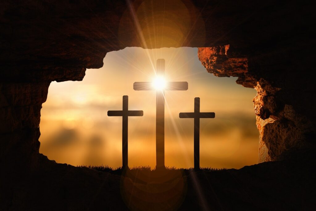A representation of Good Friday, with 3 crosses viewed from inside a dark cave. Dark clouds are gathering on the horizon, with the sun at the point where the two pieces of Jesus' cross are connected.