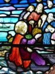 A stained-glass image of Jesus, in a boat, speaking to people